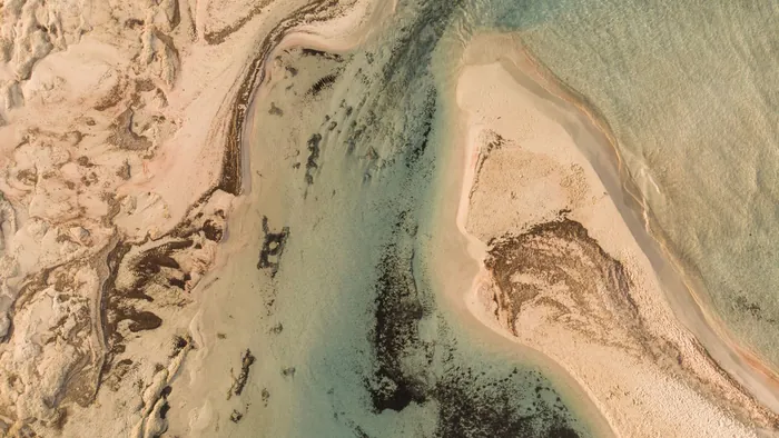 Aerial view of the pink-tinged sand and shallow turquoise channels of Elafonisi on Crete's southwest coast