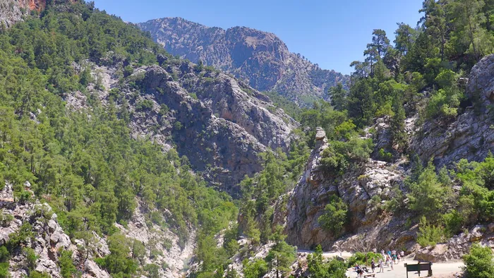 Walkers on the trail through a steep, pine-clad gorge in the White Mountains of Crete on the Samaria route